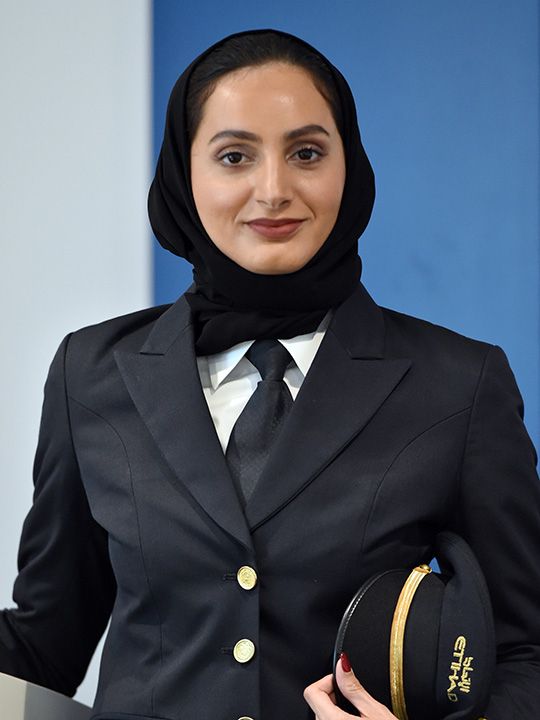 a woman wearing a suit and holding a hat