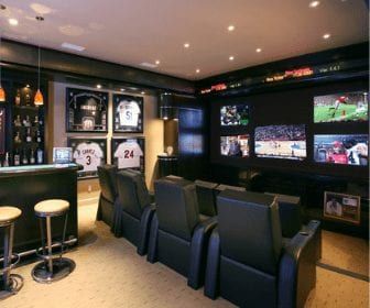 a sports themed home bar with seats and televisions