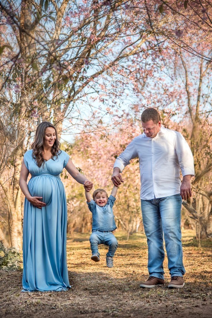 a man and woman holding the hand of a baby boy