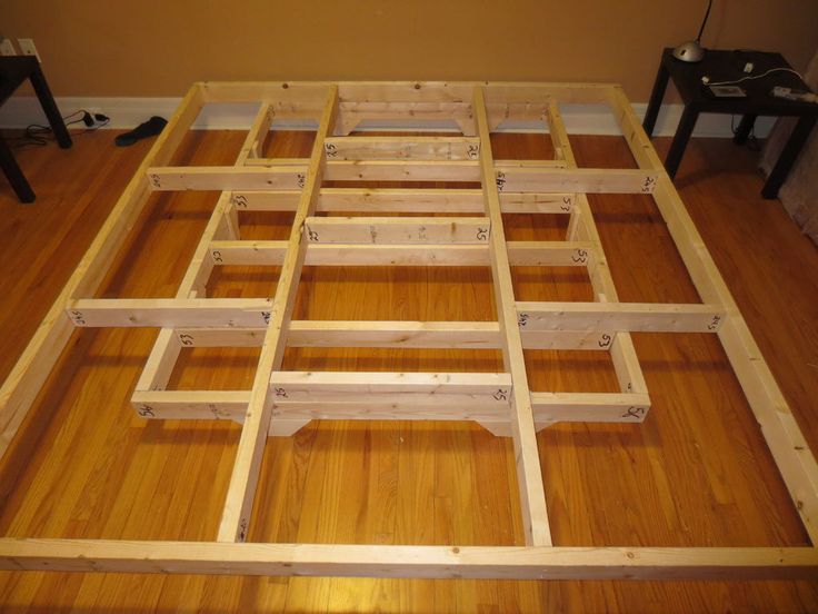 an unfinished bed frame sitting on top of a hard wood floor