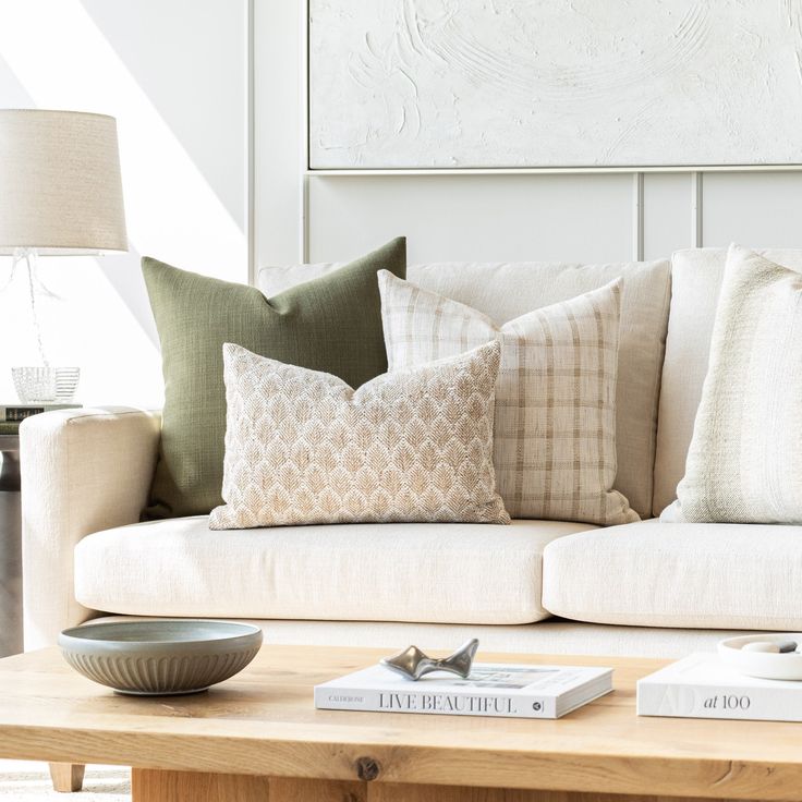 a couch with pillows on top of it in a living room next to a coffee table