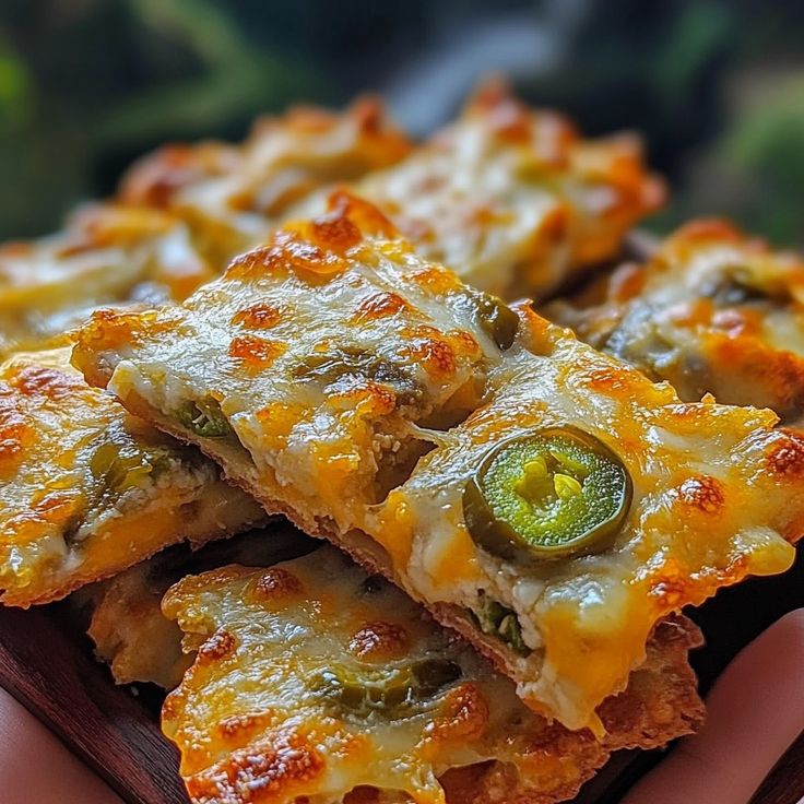 several pieces of pizza with cheese and green peppers on top, held in a person's hand