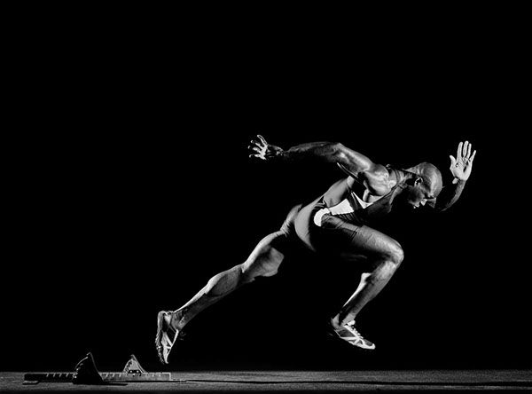 a man is running in the dark with his legs spread out and one leg bent