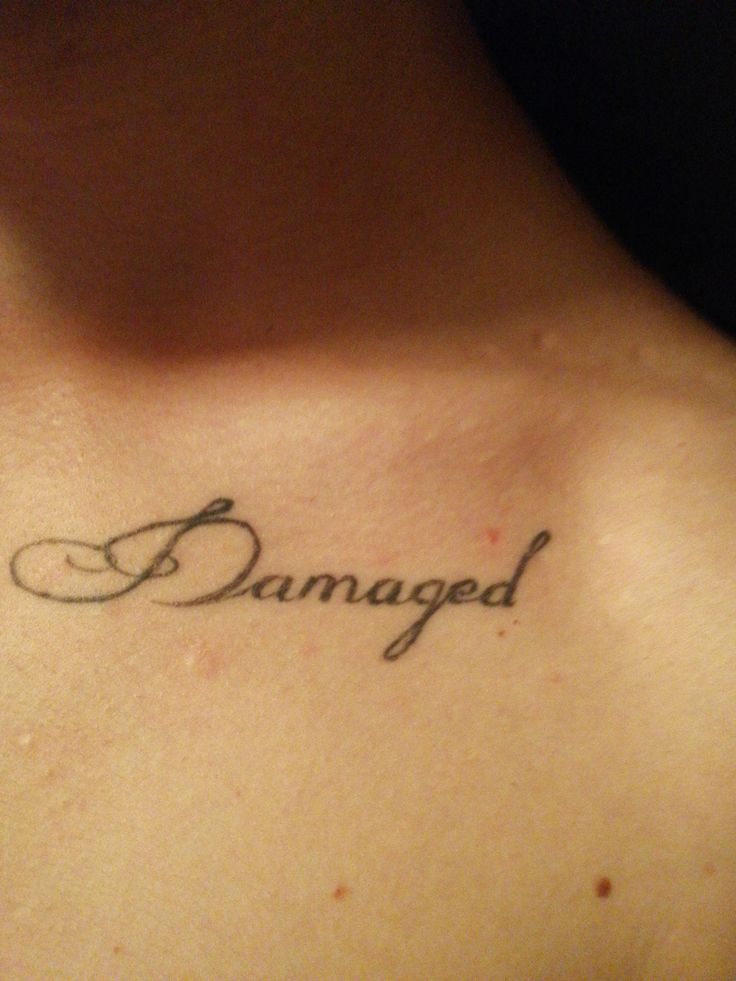 a person with a tattoo on their chest that says,'damaged'in cursive writing