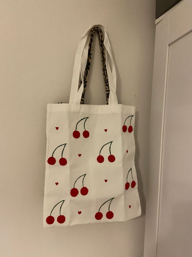 a white bag with cherries on it hanging from the wall