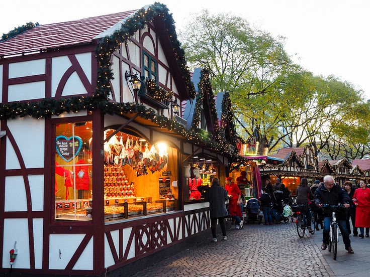 people are walking and riding bicycles in front of a building with christmas decorations on it