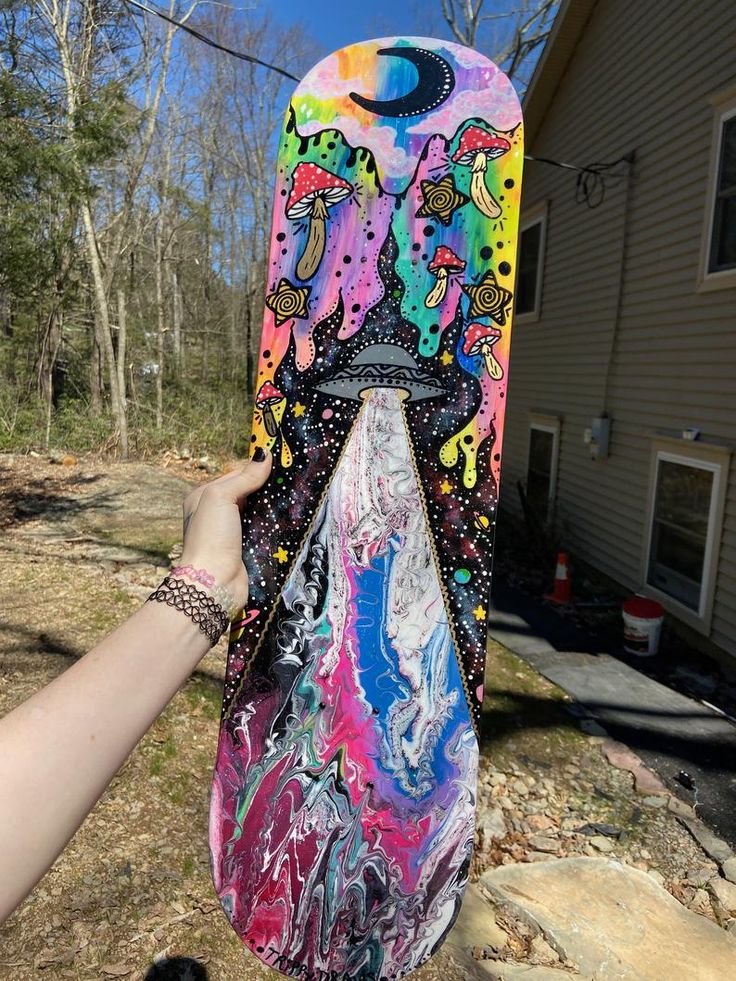 a person holding up a colorful skateboard in front of a house