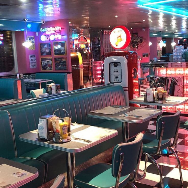 the interior of a restaurant with tables and chairs, neon lights on the ceiling and checkered flooring