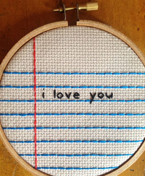 i love you written in black ink on a white and blue striped cross stitched canvas