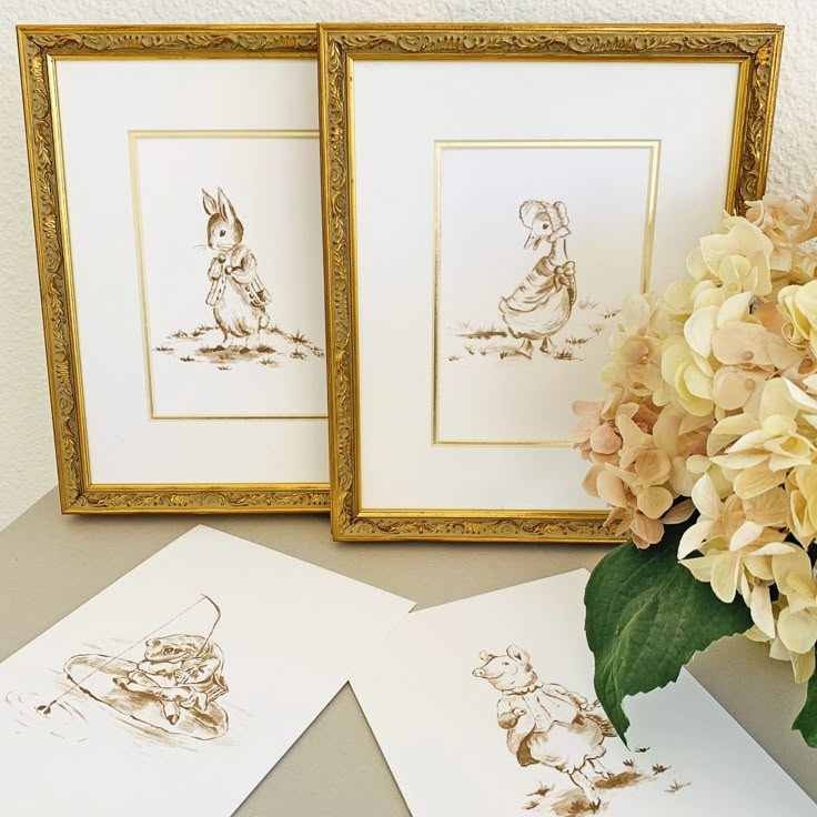 three framed pictures sitting on top of a table next to flowers