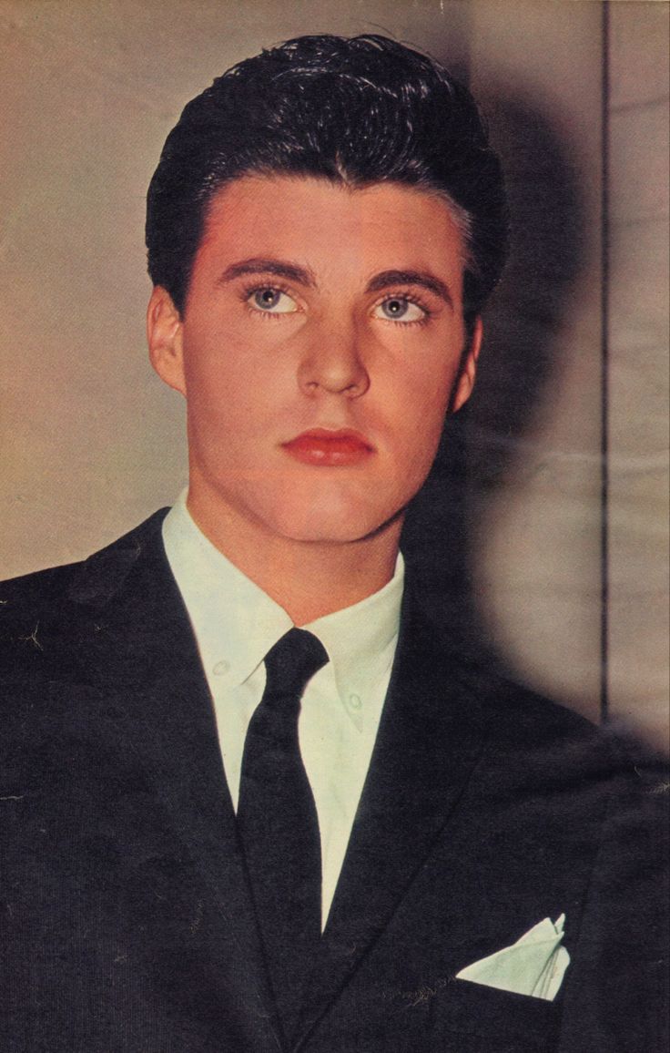 a young man in a suit and tie posing for a photo with his eyes wide open