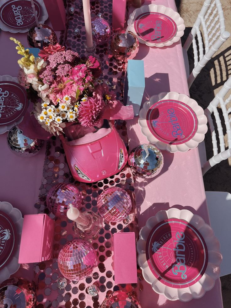 the table is set with pink plates and cups