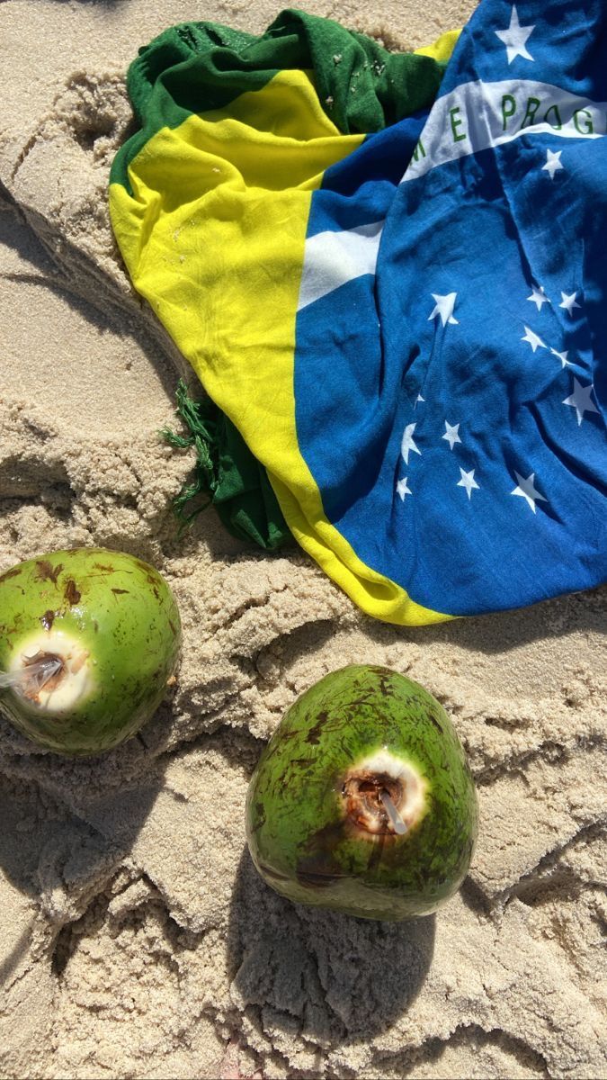 two coconuts on the sand with a flag in the background