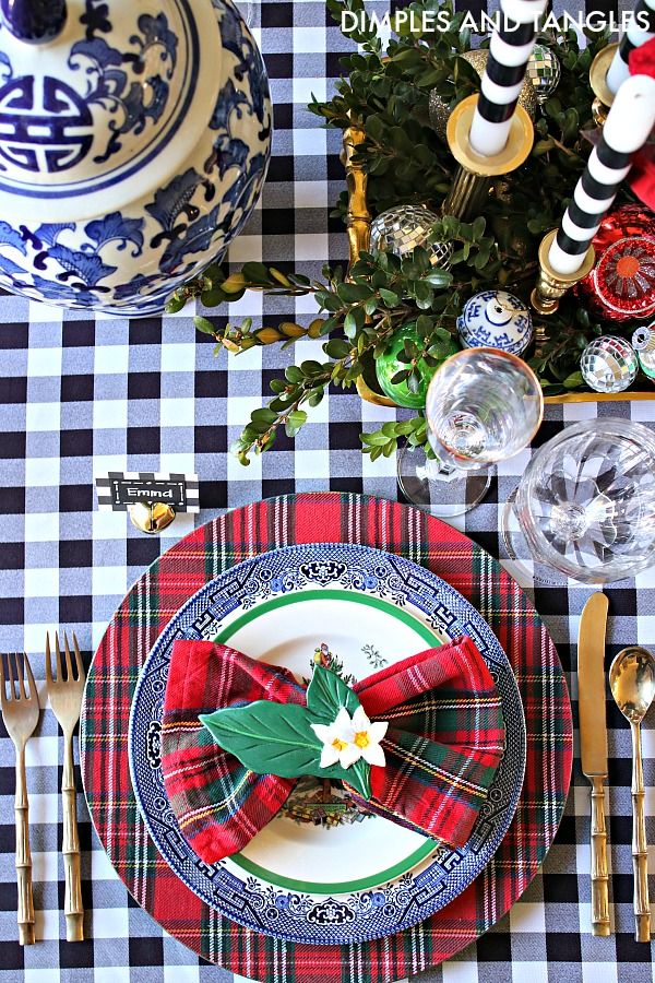 the table is set for christmas dinner with plaid napkins