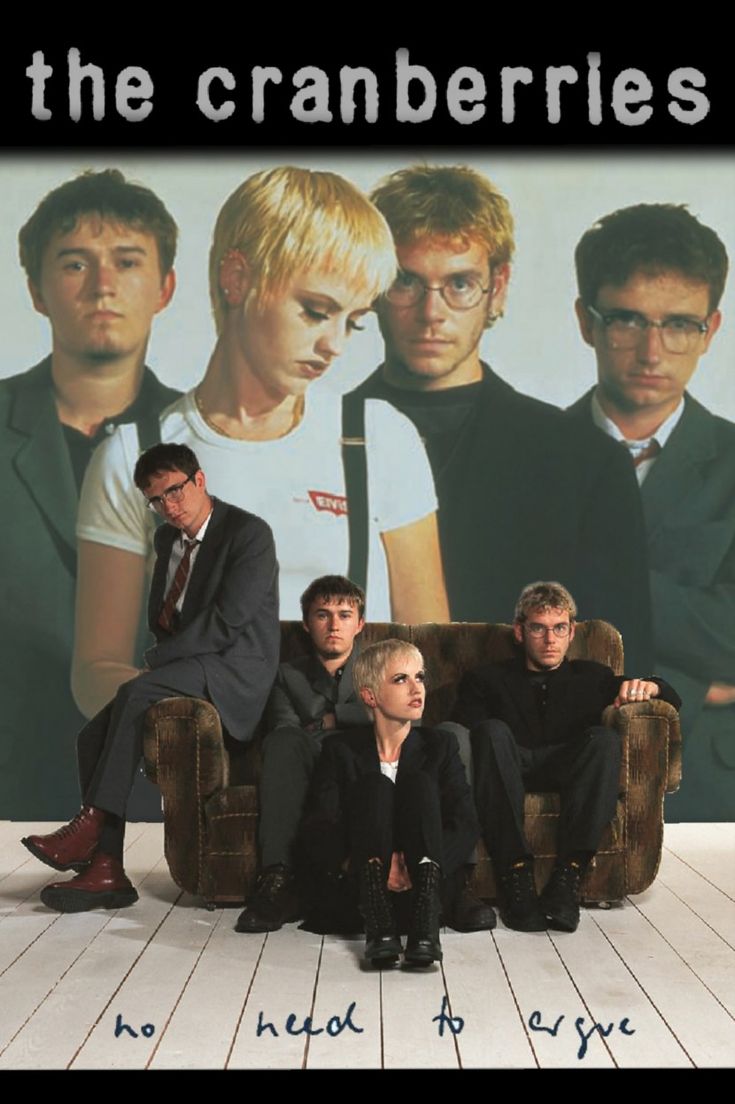 the cranberries sitting on a couch in front of a poster