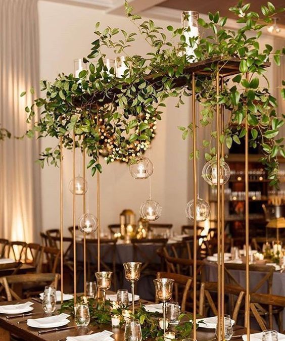 the tables are set with place settings and centerpieces, along with greenery