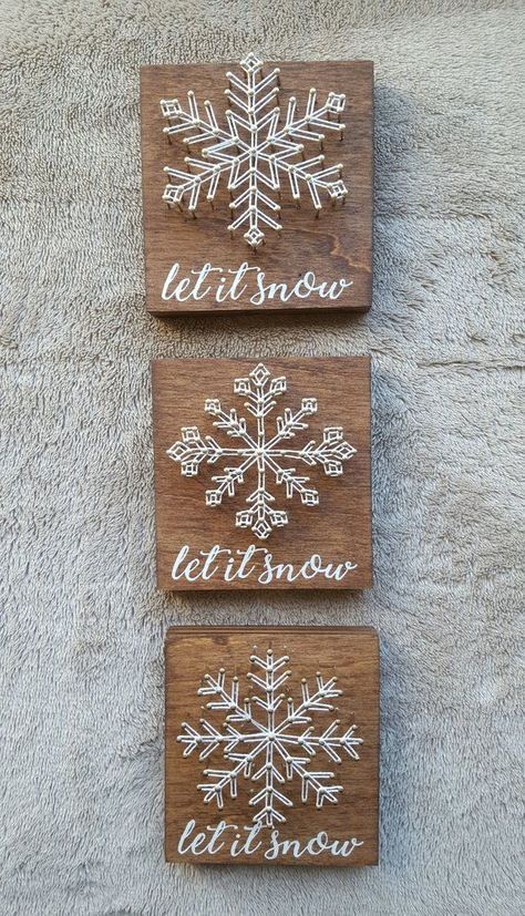 two wooden signs with snowflakes on them sitting next to each other in front of a white rug