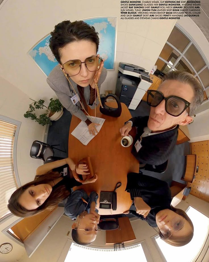 four people sitting around a table with their hands on the top