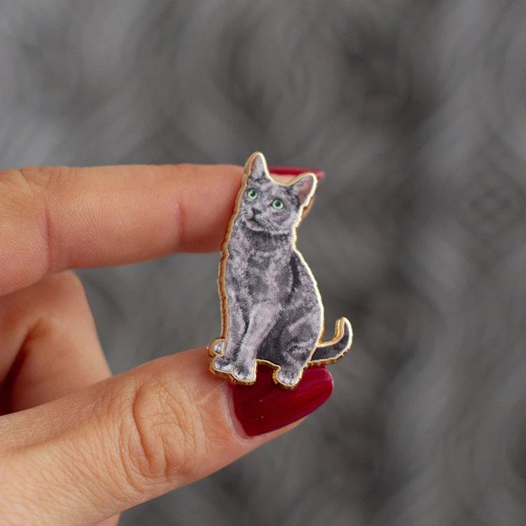 a cat brooch sitting on top of a finger