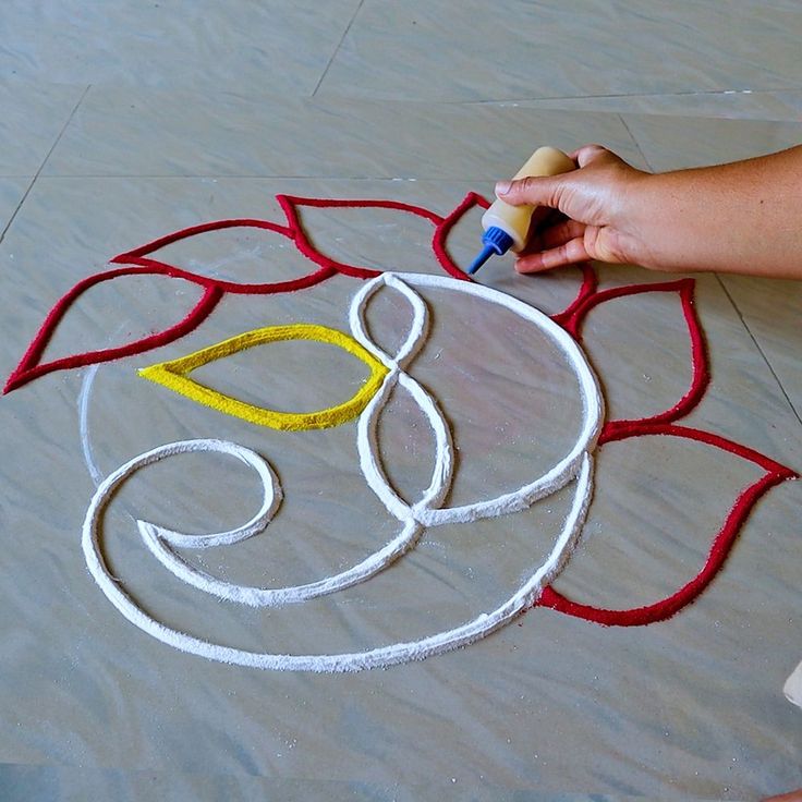 someone is drawing on the ground with crayons and glue to create a flower