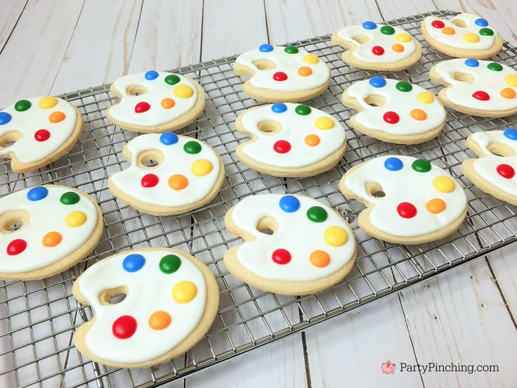 decorated sugar cookies on a cooling rack with white frosting and colorful icing dots