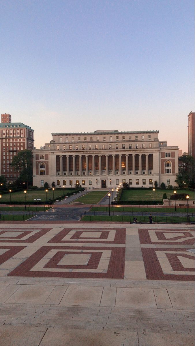 a large building with many windows and lights on it's sides in the evening