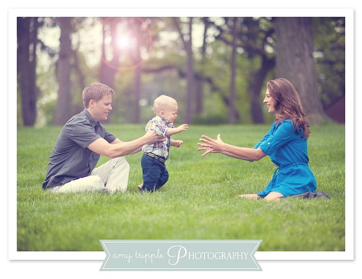 a man, woman and baby playing with each other in the grass on a sunny day