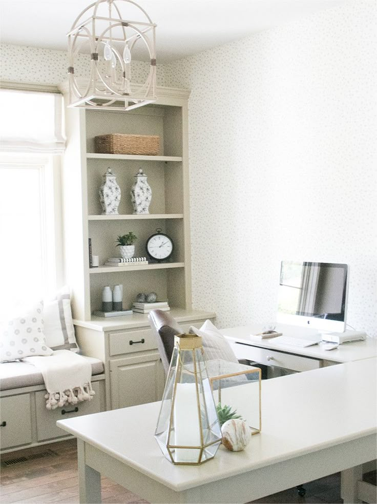 a white desk with a computer on top of it in front of a book shelf