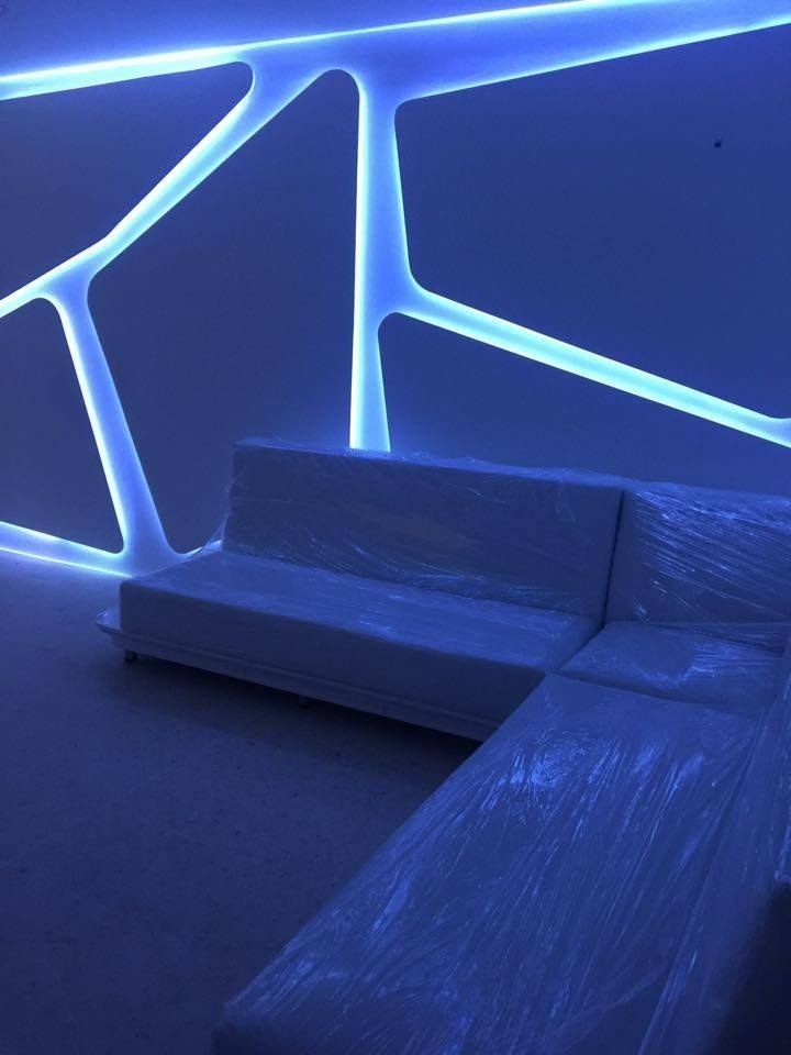 a white couch sitting in front of a blue wall with lights on it's sides