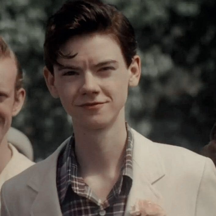 two young men standing next to each other in front of some green trees and bushes