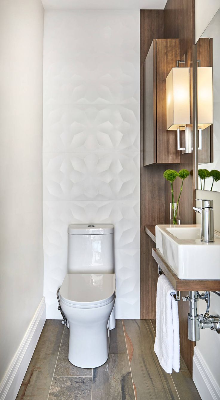 a white toilet sitting next to a sink in a bathroom under a mirror and lights