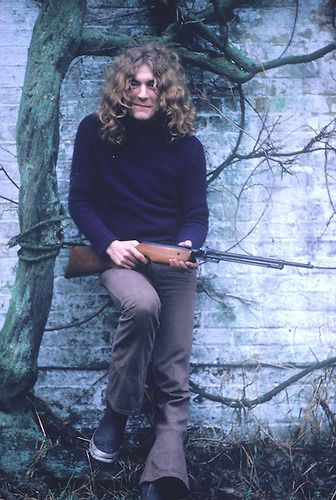 a man sitting on top of a wooden bench next to a tree and brick wall