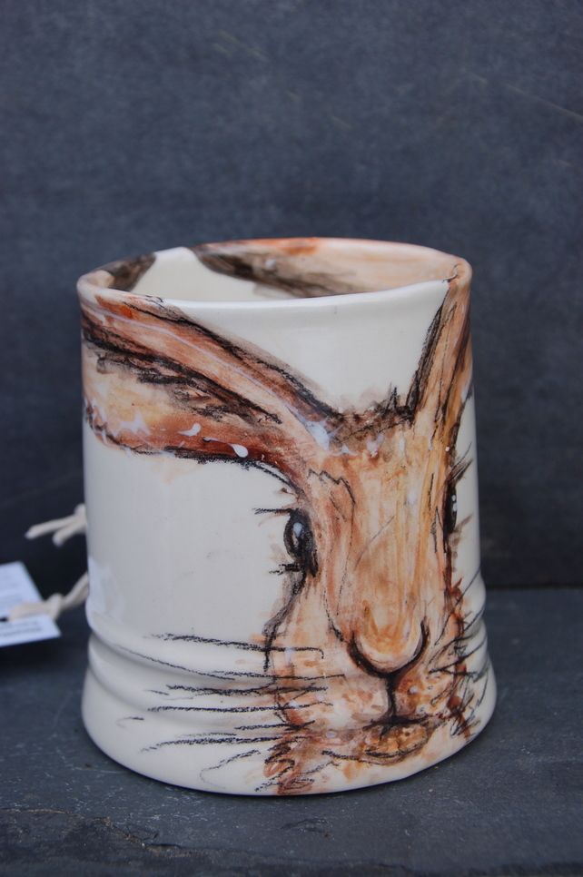 a coffee mug with a drawing of a rabbit on it's side and the lid