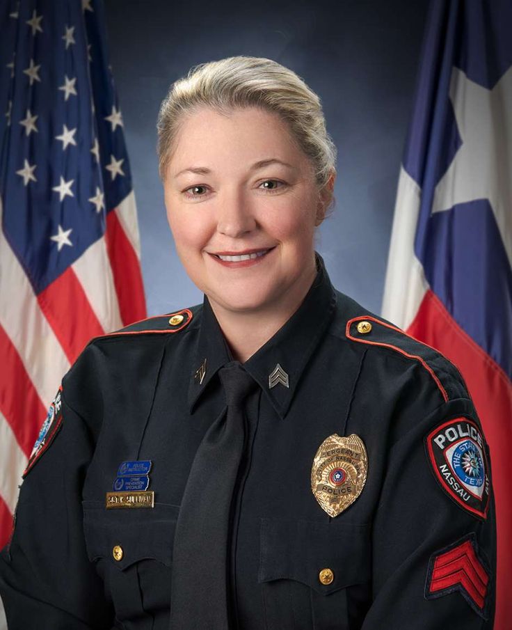 a female police officer in front of two american flags