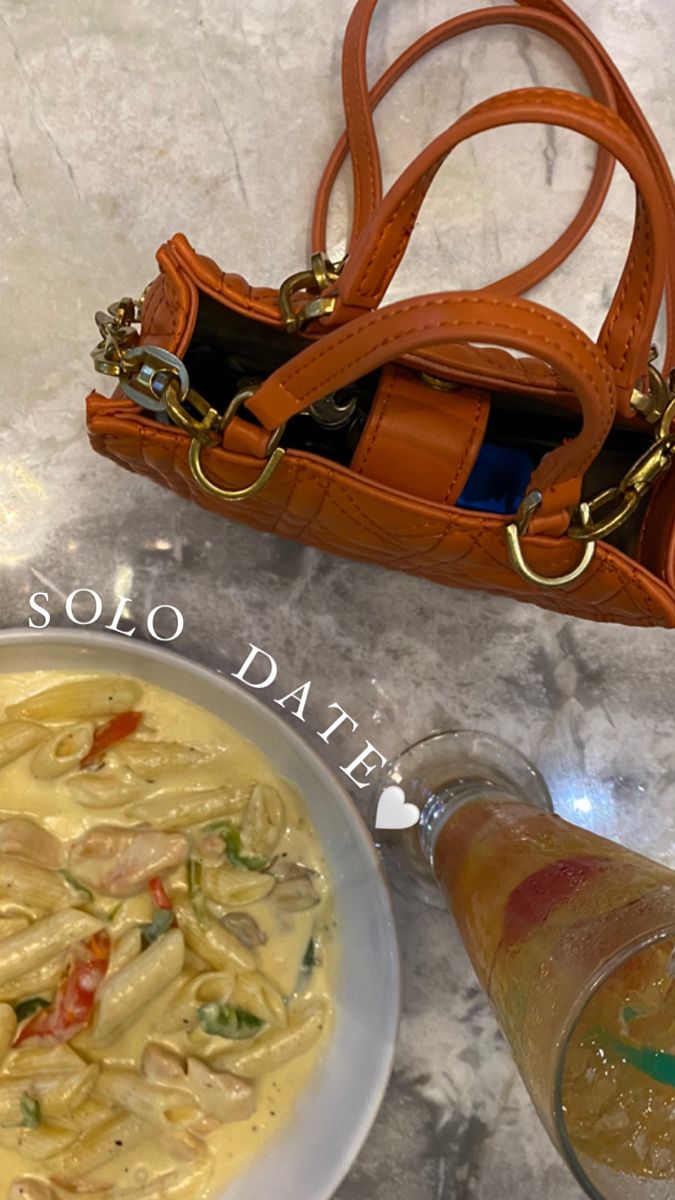 a bowl of pasta and a handbag on a table