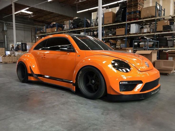 an orange car parked in a garage with lots of boxes on the shelves behind it