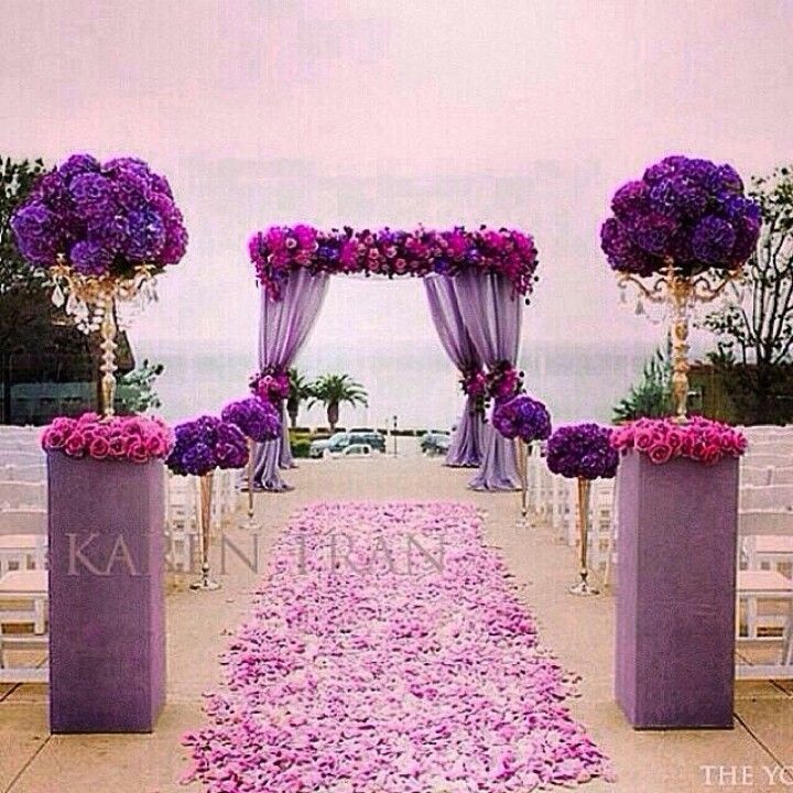 an outdoor ceremony setup with purple flowers and draping on the aisle, overlooking the ocean