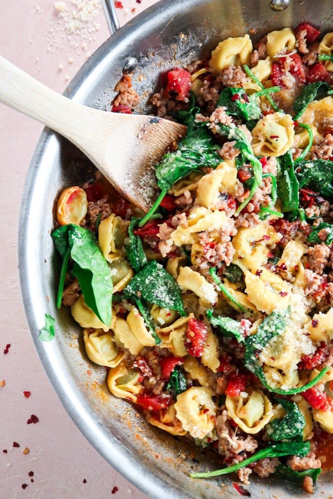 a pan filled with pasta, spinach and meat