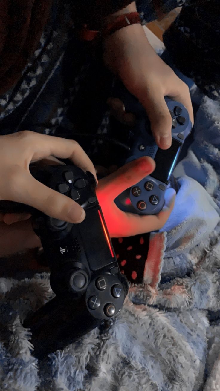 a person holding a video game controller on top of a fluffy blanket in the dark