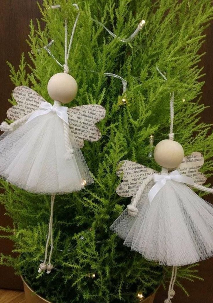 two angel ornaments sitting on top of a potted plant next to a book page ornament