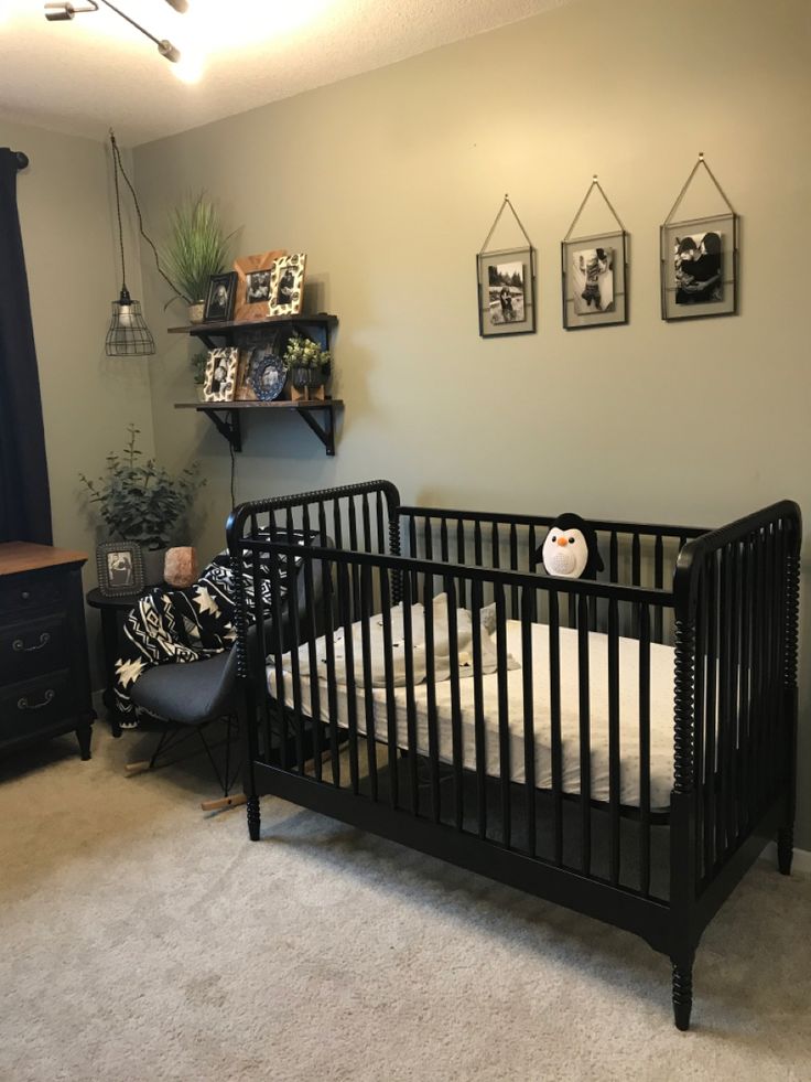 a black crib in a room with pictures on the wall