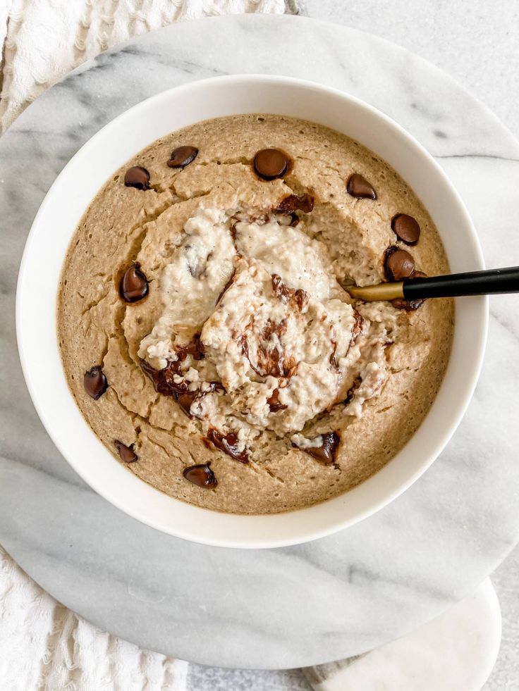 a white bowl filled with chocolate chip cookies and ice cream on top of a marble table