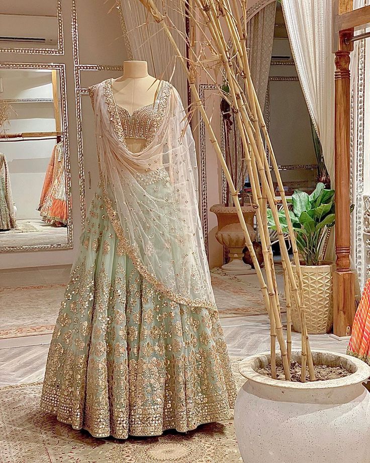 a dress on display in front of a mirror and potted plant with dried grass