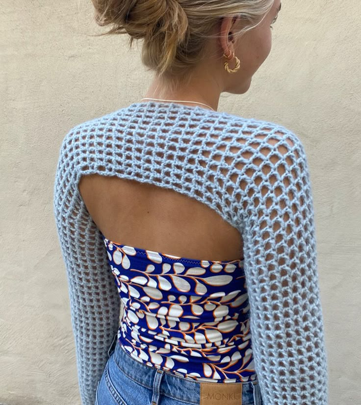 a woman with her back to the camera, wearing jeans and a blue top that has white flowers on it