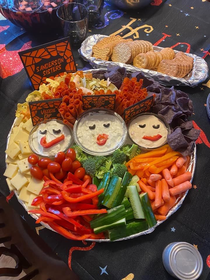 a platter filled with vegetables and crackers on top of a black table cloth