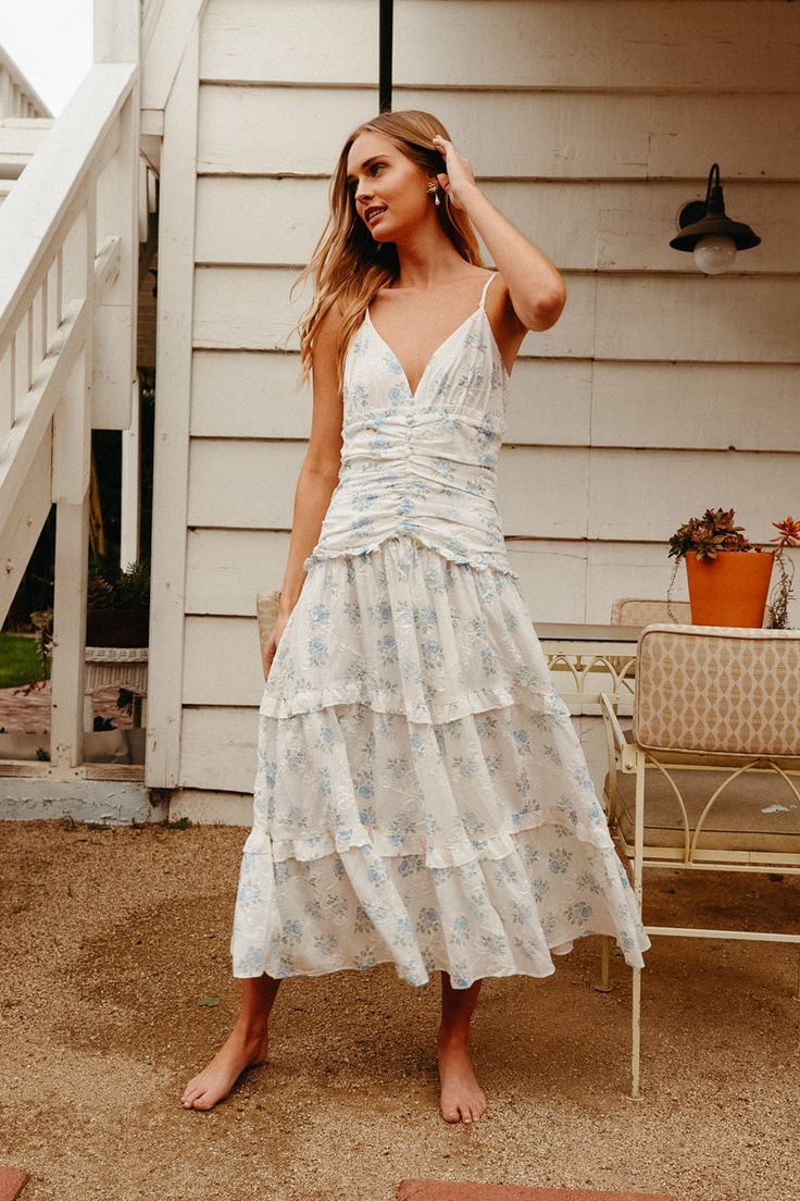 white ruched tiered maxi dress with blue floral print | english floral print dress Affordable Sleeveless Sundress By Urban Outfitters, Flowy Ruched Dresses For Gatherings, Flowy Ruched Sundress For Garden Party, Feminine Cream Tiered Dress, Spring Maxi Dress With Ruched Ruffled Straps, Cream Tiered Skirt Dress For Brunch, Spring Maxi Dress With Ruched Details And Ruffled Straps, Spring Dresses With Ruched Bodice And Ruffled Straps, Fitted Tiered Dress For Vacation