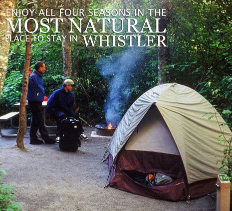 two men standing next to a tent in the woods with fire coming out of it