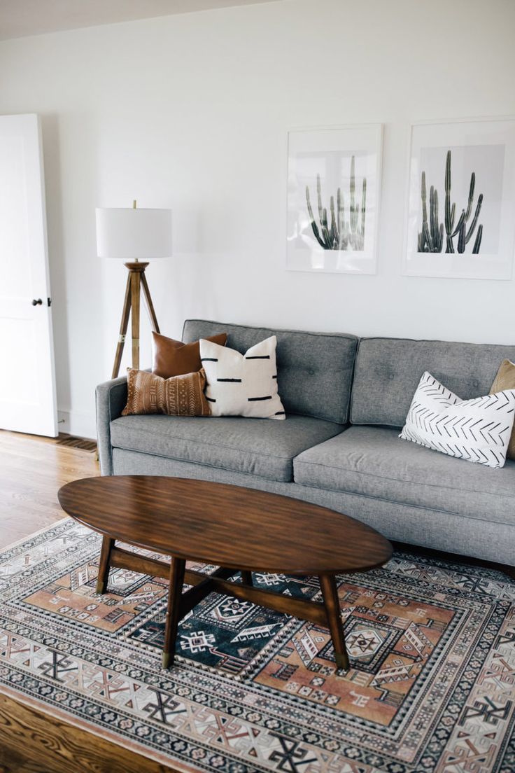 a living room with a gray couch and wooden coffee table in front of two pictures on the wall