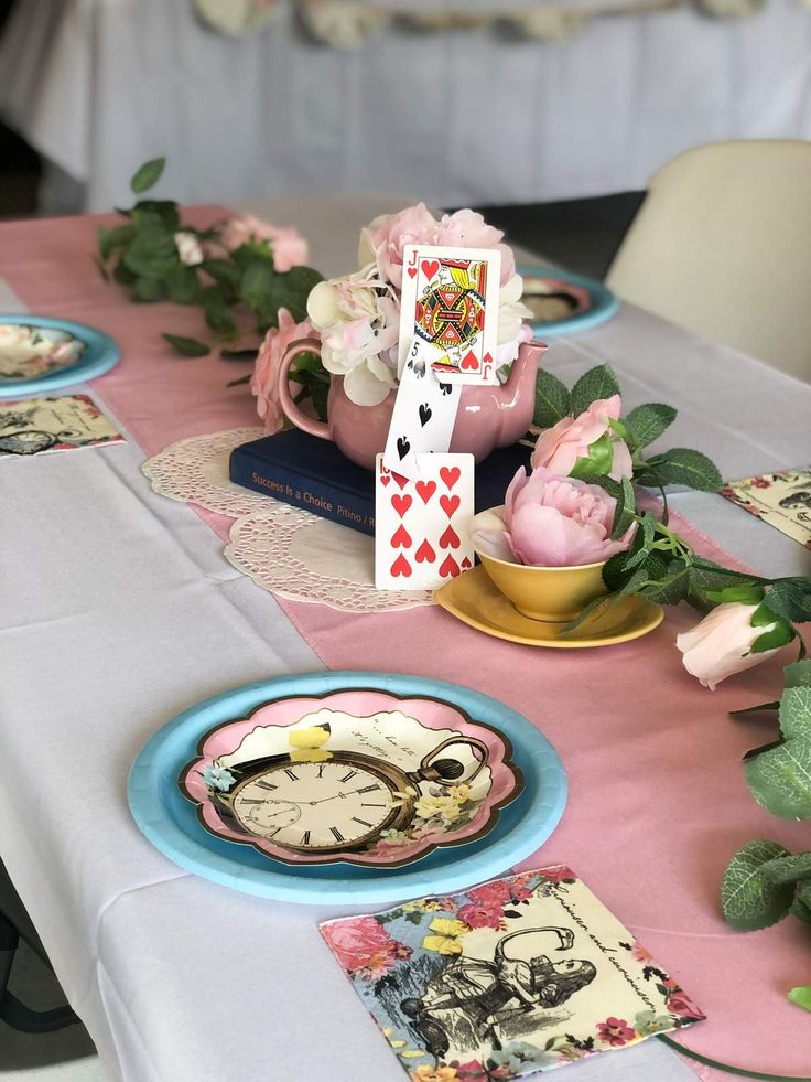 the table is set with pink and blue plates, cups, and napkins on it