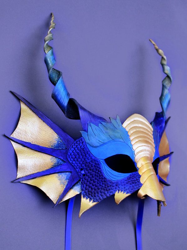 a blue and yellow dragon mask with horns on it's head, against a purple background